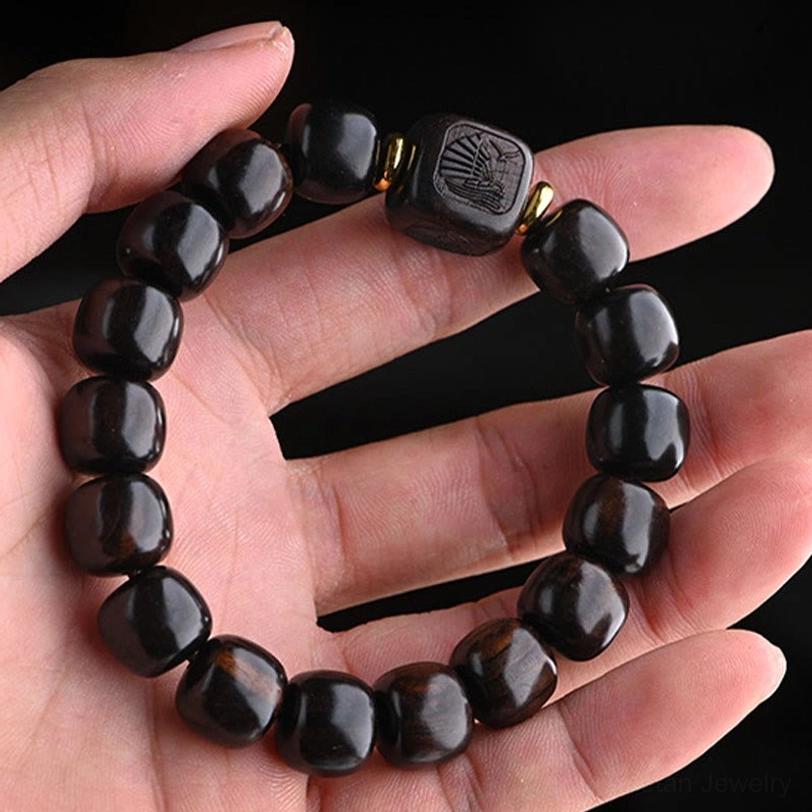 Tibetan ebony wood bracelet worn on hand showing polished beads with carved square accents and gold spacers