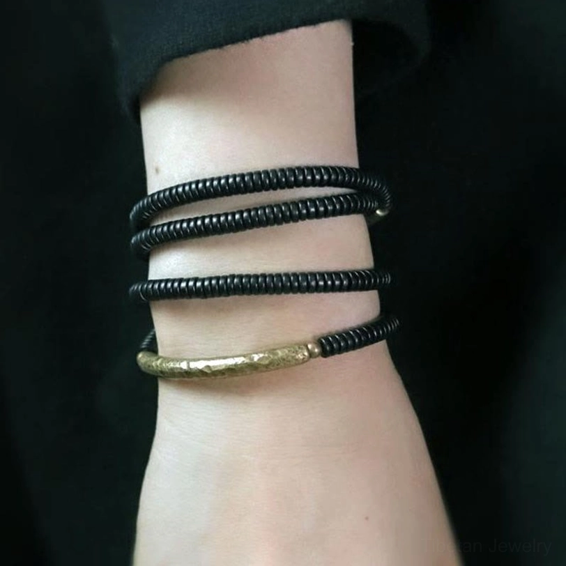 Multi-layered ebony wood beaded bracelet worn on wrist, four strands of black disc beads showing wearable styling