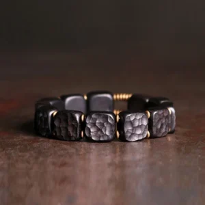 Ebony wood copper balance bracelet flat lay view with square beads and bronze gold spacers on vintage brown surface