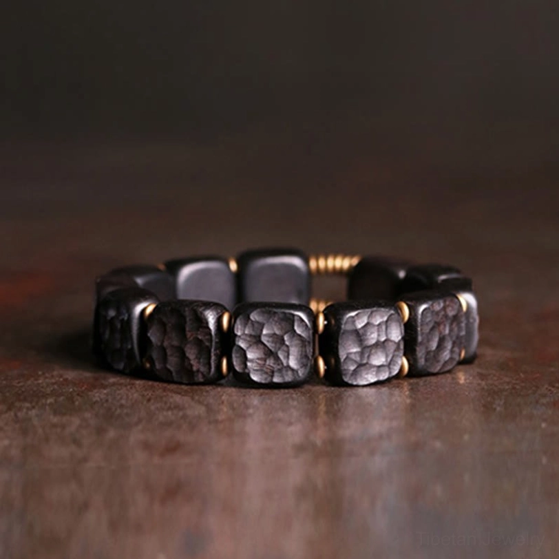 Ebony wood copper balance bracelet flat lay view with square beads and bronze gold spacers on vintage brown surface