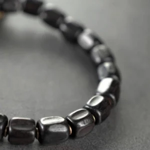 Close-up side view of polished ebony wood barrel beads with vintage copper accents