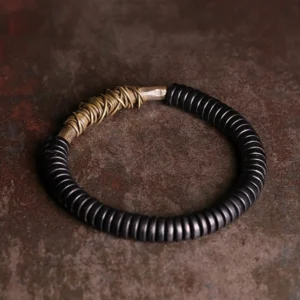 Ebony wood copper bracelet oblique angle view highlighting twisted copper wire decoration on vintage background