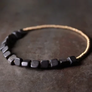 Flat lay frontal view of handcrafted ebony wood copper double wrap bracelet set, featuring polished square black wood beads with bronze metal spacers arranged in linear pattern