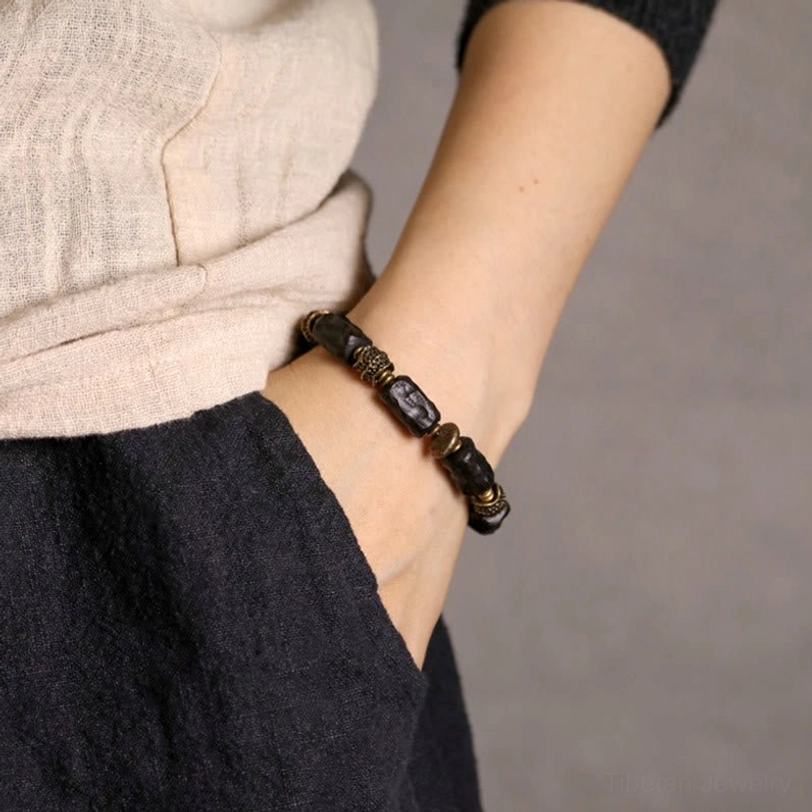 Ebony wood copper beaded bracelet worn on wrist with casual layered clothing pocket showing practical daily wear styling
