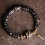 Ebony wood copper couple bracelet flat lay overhead view showing antique bronze hardware and spike pendant on dark surface