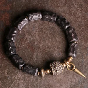 Ebony wood copper couple bracelet flat lay overhead view showing antique bronze hardware and spike pendant on dark surface