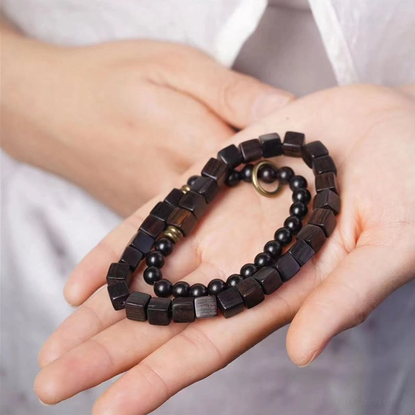 Ebony wood double wrap bracelet with alternating square and round beads displayed in hands, showing bronze metal spacers and clasp detail