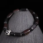 Ebony wood Dzi bead balance bracelet with two-eye Dzi and rectangular dark wooden beads displayed on wooden stand - top view