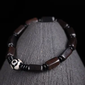 Ebony wood Dzi bead balance bracelet with two-eye Dzi and rectangular dark wooden beads displayed on wooden stand - top view