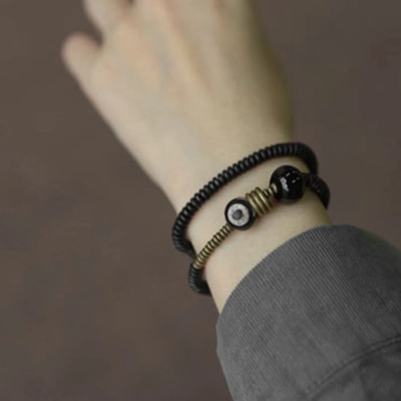 Tibetan Dzi bead ebony wood bracelet worn on wrist - side view with gray sleeve