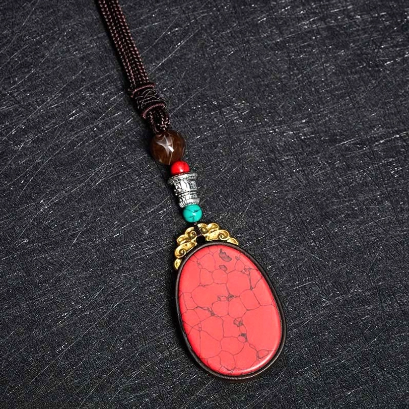 Ebony wood oval necklace pendant closeup showing tribal carving and natural wood patina