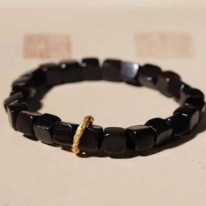 Ebony wood square bead bracelet with twisted copper clasp on light brown background with Chinese seal stamps