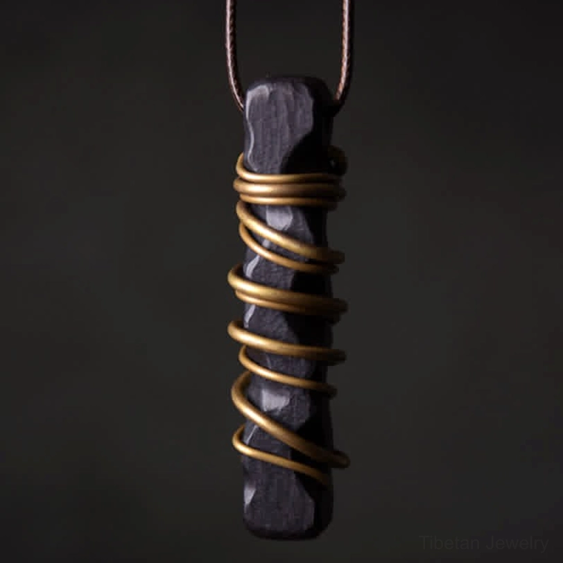 Handcrafted ebony wood Tibetan zen circle pendant with brass wire wrapping, close-up front view showing natural wood grain texture and metal detail
