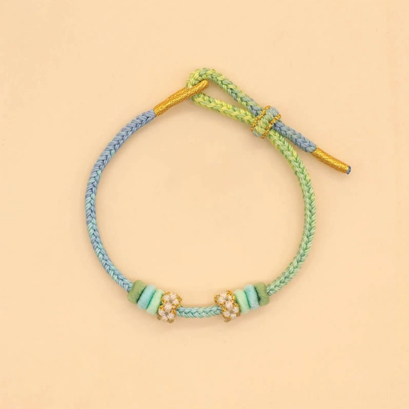 Gradient pastel handwoven peace knot bracelet in blue, green and yellow tones with flower decorative elements