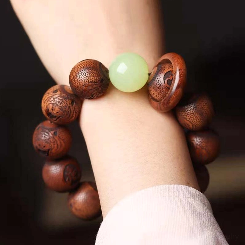 Close-up side view of engraved rosewood tiger bracelet on wrist highlighting carved wooden ring and luminous green spacer bead