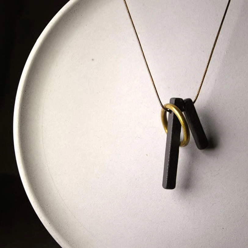 Handcrafted Enso pendant arranged on white matte ceramic plate low angle view