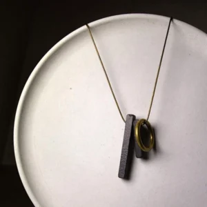 Handmade ebony wood Enso pendant close-up on white ceramic plate showing wooden details and brass ring