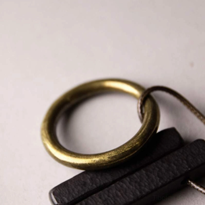 Macro detail shot of ebony wood Enso pendant showing brass gold ring and wood texture