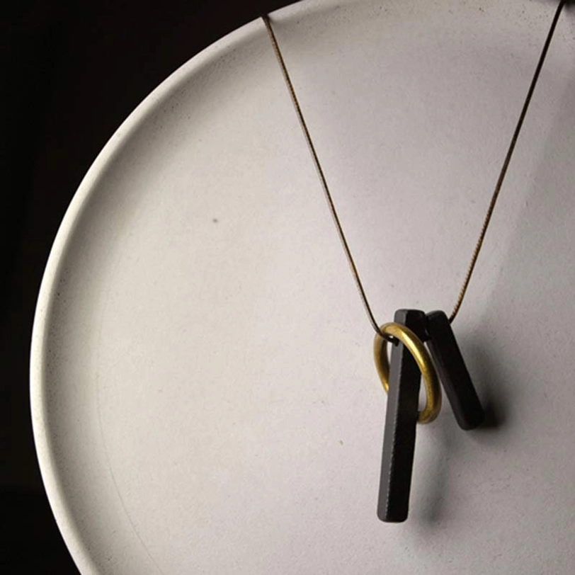 Sleek ebony wood Enso pendant necklace on white ceramic plate minimalist display