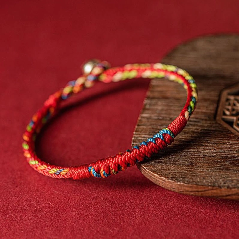 Authentic handmade Tibetan five-color protection bracelet on wooden mat showing woven thread texture