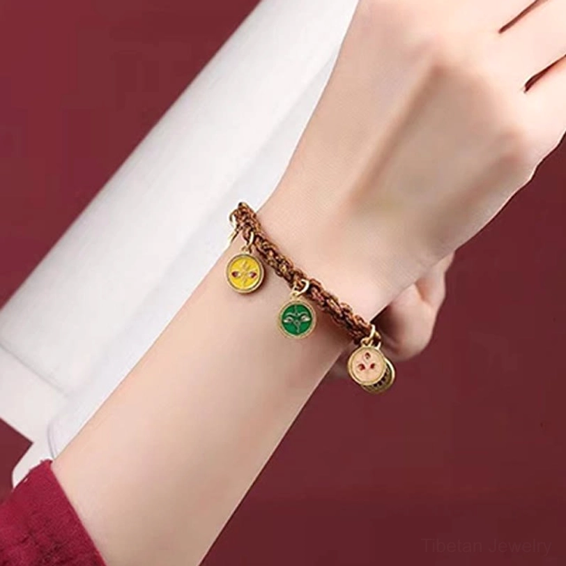 Tibetan wealth bracelet detail showing colored enamel charms on braided cord