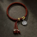 925 sterling silver five directions wealth god bracelet with red braided cord and silver charm, flat lay view on dark brown background