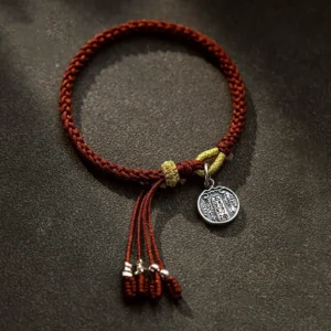 925 sterling silver five directions wealth god bracelet with red braided cord and silver charm, flat lay view on dark brown background