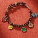 Five God of Wealth Tibetan braided bracelet flat lay showing five colored enamel pendants on woven cord