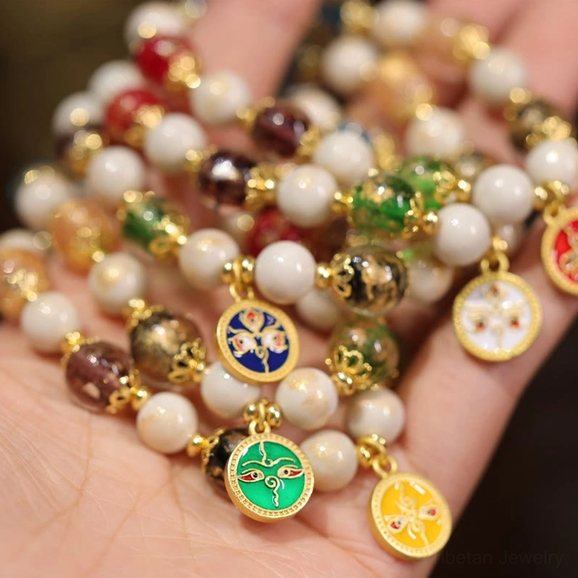 Tibetan Five Gods of Wealth bracelet beads and enamel charm pendants held in palm showing detailed craftsmanship and mixed bead materials
