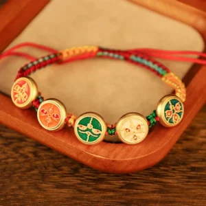 Five gods of wealth prosperity bracelet featuring dual-tone braided rope and round enamel deity charms with gold spacer beads on velvet tray