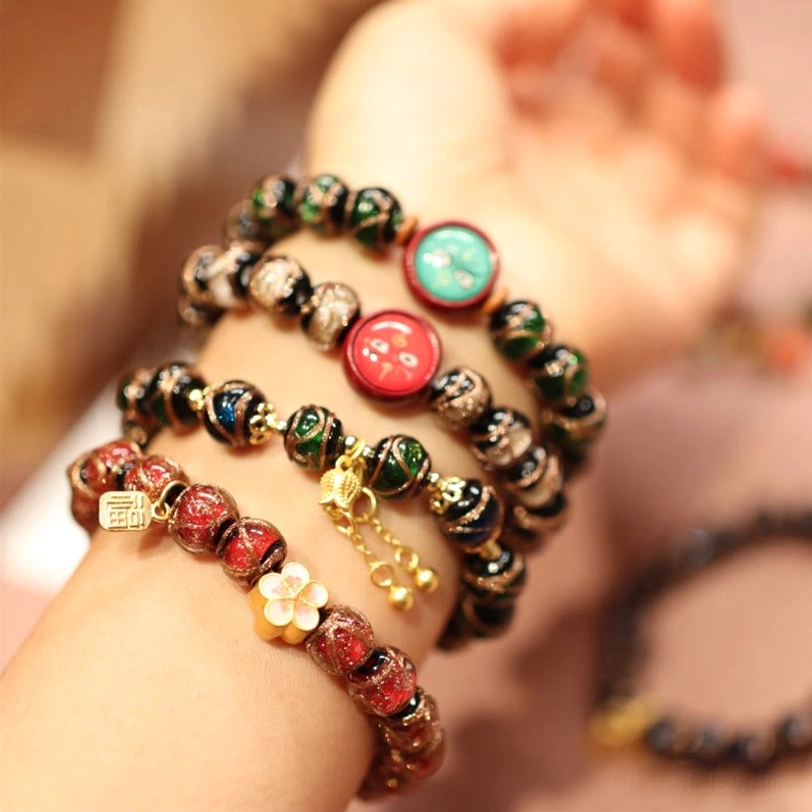 Multiple Five Gods of Wealth Tibetan bracelets displayed on wrist showing enamel beads, gold charms and fortune ornaments