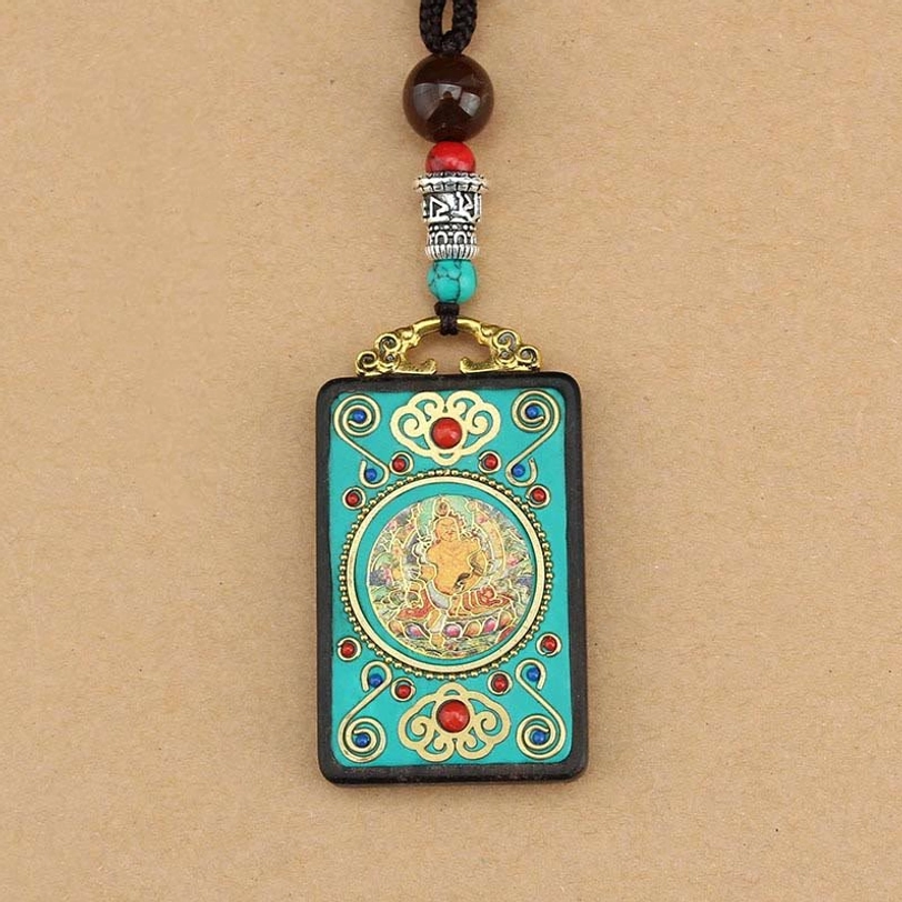Tibetan wealth thangka pendant necklace with beaded string and metal hardware in flat lay on tan paper background