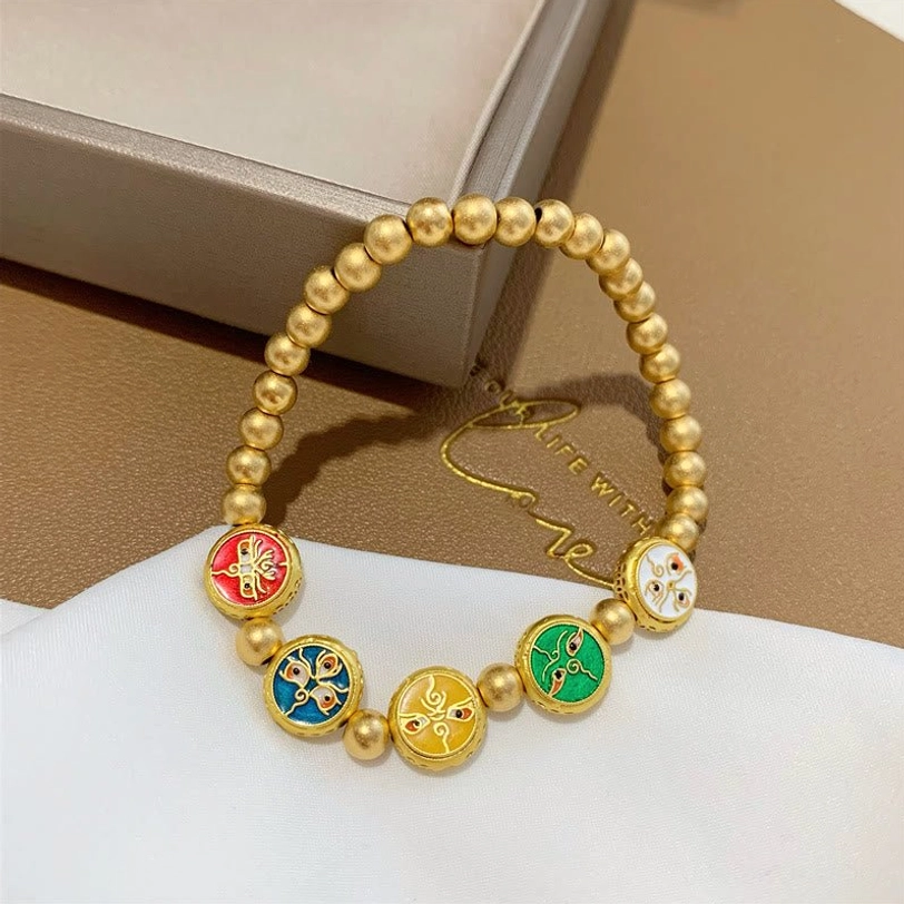 Single five gods of wealth Tibetan prosperity bracelet with matte gold copper beads and colorful enamel charm beads on white cloth and brown paper box