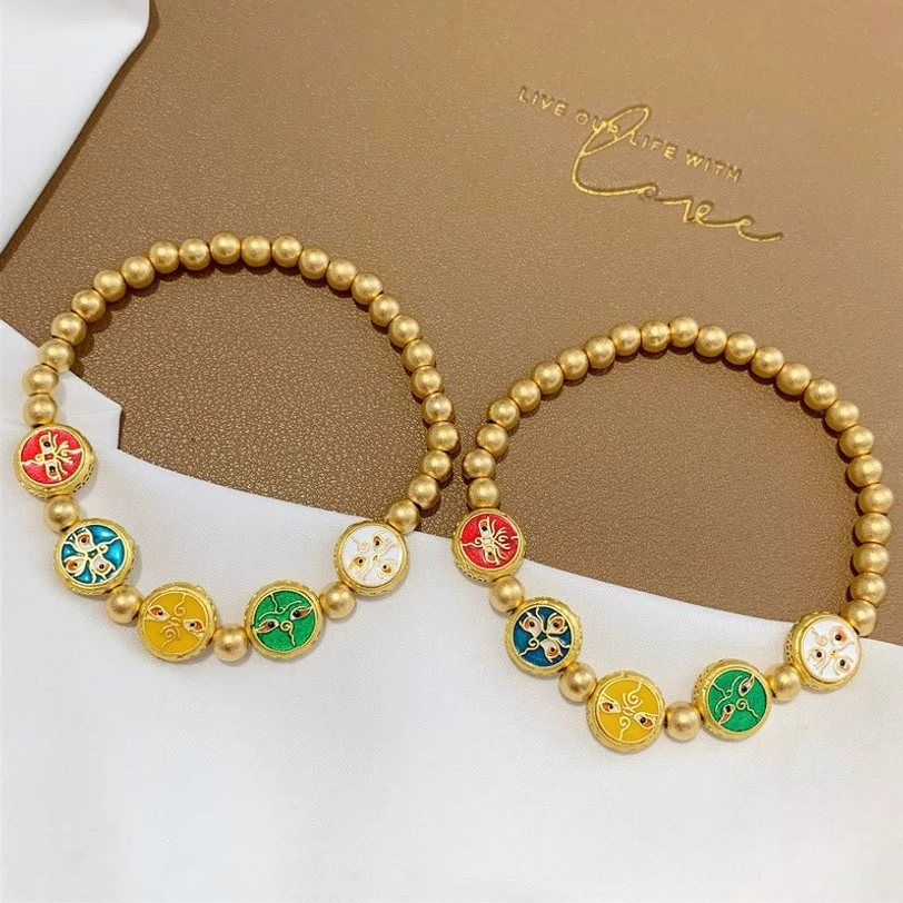 Pair of five gods of wealth Tibetan copper beads luck bracelets displayed together on brown card with white fabric backdrop, showing all enamel charm details