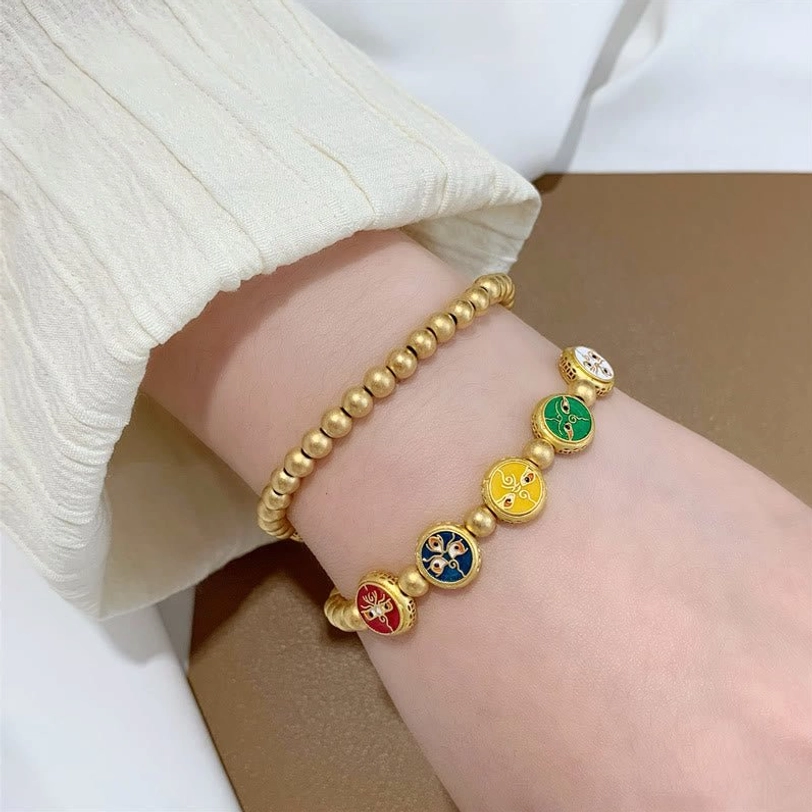 Two five gods of wealth Tibetan prosperity bracelets worn on wrists against white knitted sleeve background, showing full charm sequence and wearable fit