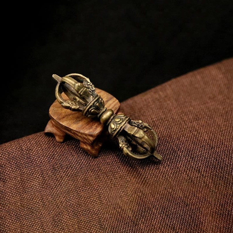Compact five-prong Tibetan Vajra Dorje with aged bronze metal finish and carved religious design patterns on linen