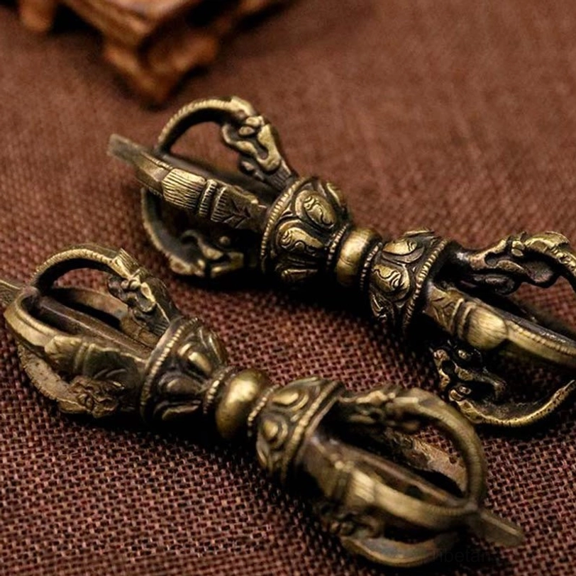 Two five-prong Tibetan Vajra Dorje close-up overhead view displaying clear carved patterns and consistent aged bronze texture on linen