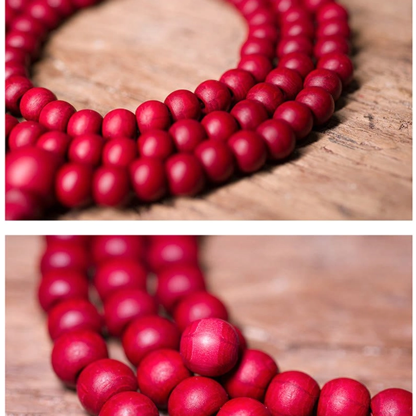 Complete strand of 108 tibetan mala prayer beads laid flat showing uniform round beads with double tassel pendant on maroon fabric background