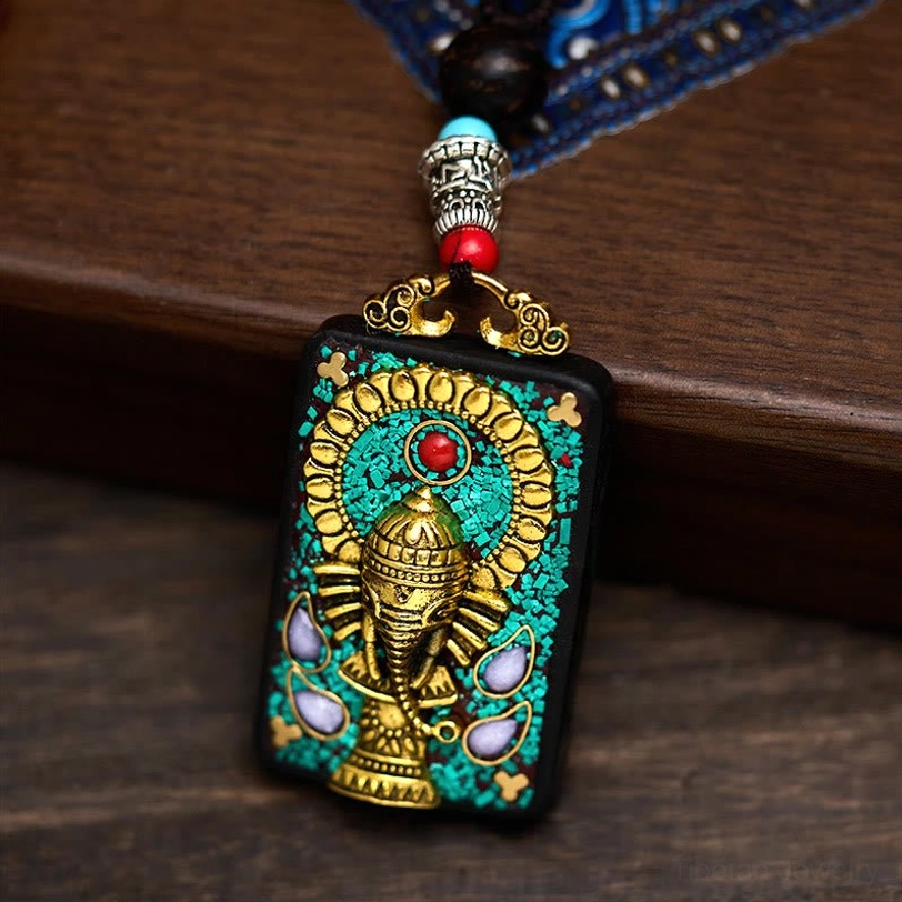 Tibetan Ganesha pendant with dark wood bead and silver-tone metal spacers, close-up detail