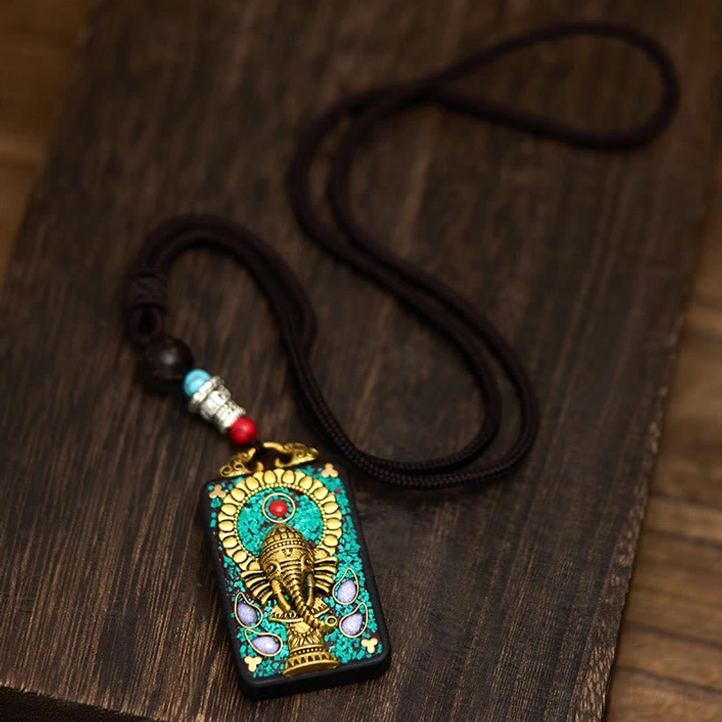 Ganesha spiritual necklace on braided rope displayed overhead on dark wood surface