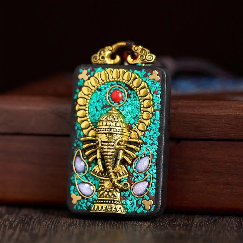 Ganesha Tibetan amulet pendant with red centerstone and gold halo frame, frontal view