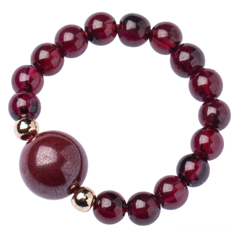 Large statement garnet and cinnabar bead ring with glossy polished finish and central bright crimson bead on wine red background