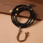 Silver Sheen Obsidian Garuda protection necklace hand-woven beads overhead view on wooden surface