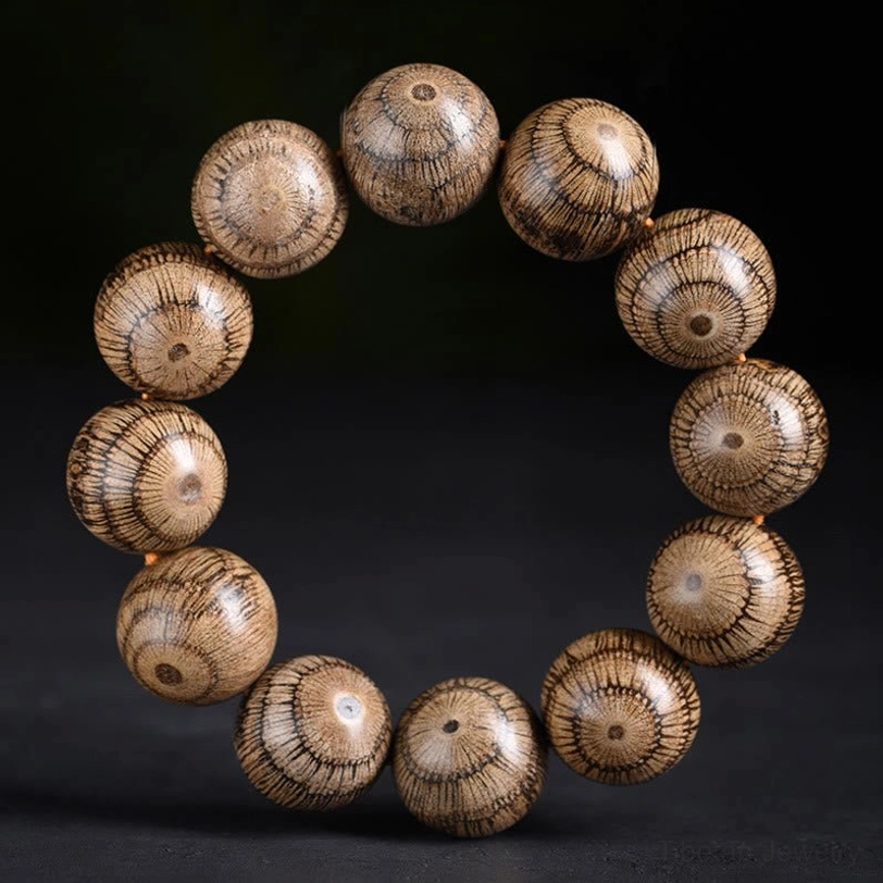 Gnetum wood beads protection bracelet overhead view with warm light brown radial grain pattern on dark background