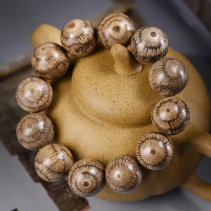 Loose natural Gnetum wood beads showing distinctive radial striped texture close-up with clay teapot styling