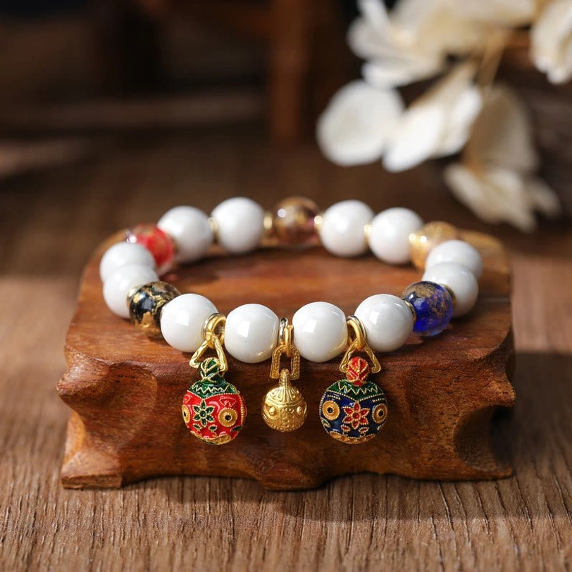 Single Pixiu charm bracelet with colorful gold silver foil glass beads displayed on wooden stand with complementary metal spacers