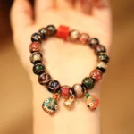 Gold Swallowing Beast Family Tibetan prosperity bracelet featuring enamel beast pendants and mixed stone beads on human hand