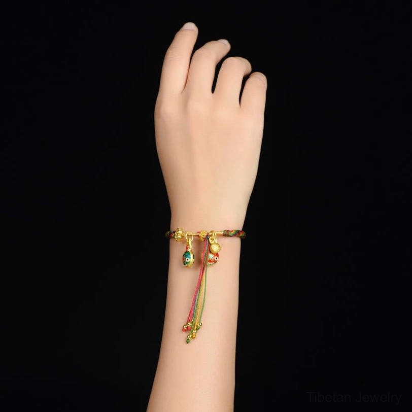 Tibetan gold swallowing beast family luck bracelet worn on wrist with decorative beaded tassel and enamel beast pendants