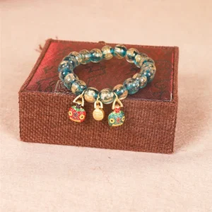 Gold Swallowing Beast Family Tibetan bracelet with three enamel charms and blue glass beads top view