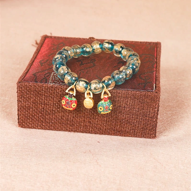 Gold Swallowing Beast Family Tibetan bracelet with three enamel charms and blue glass beads top view